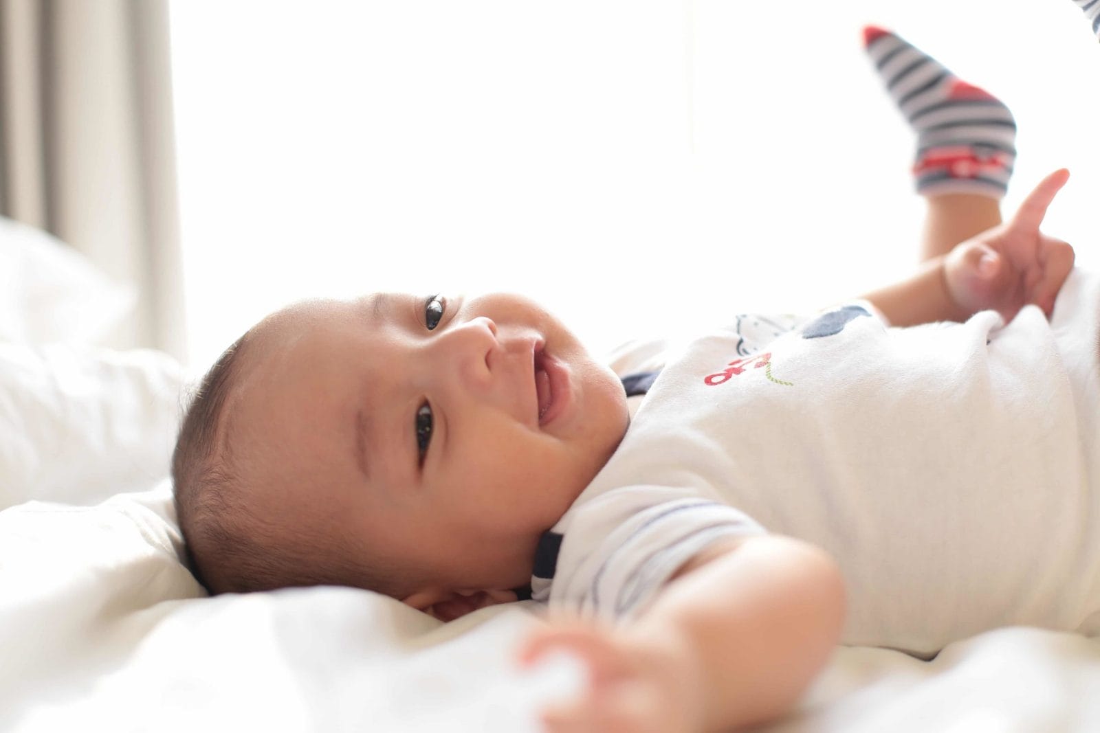 Activities for a 5-month-old: Fostering baby’s development baby lying down on bed and smiling - activities for 5-month-old