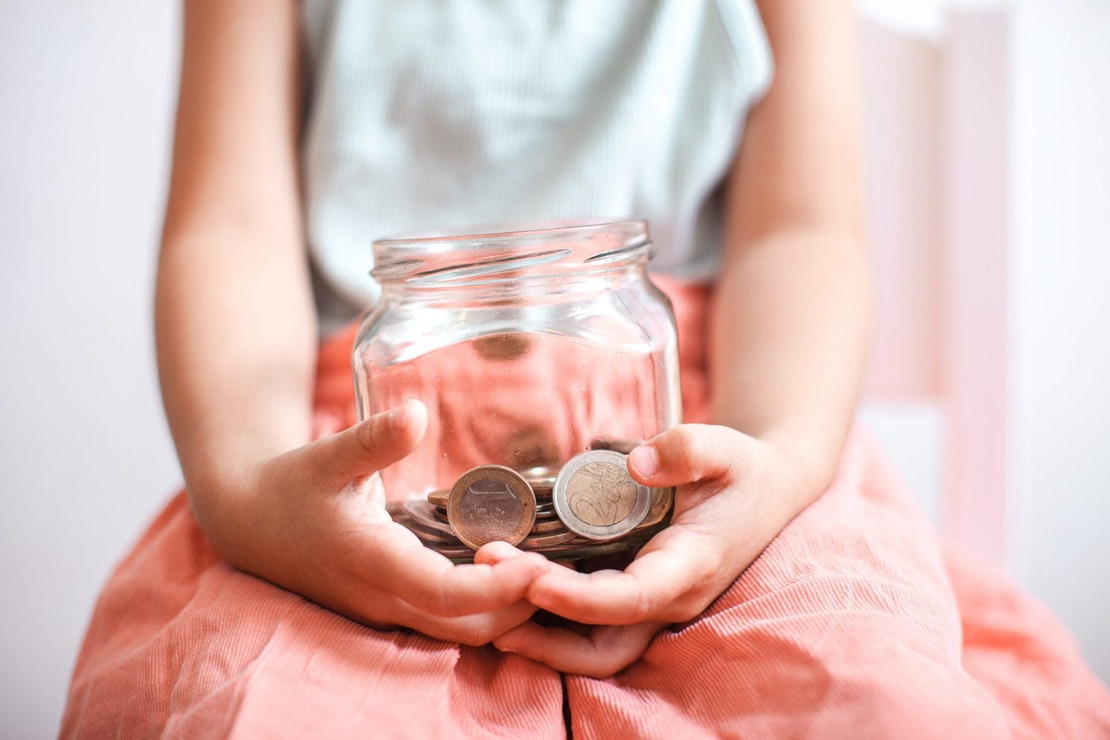 Do these 9 things to set up your child for a healthy financial future girl holding money jar- better money habits