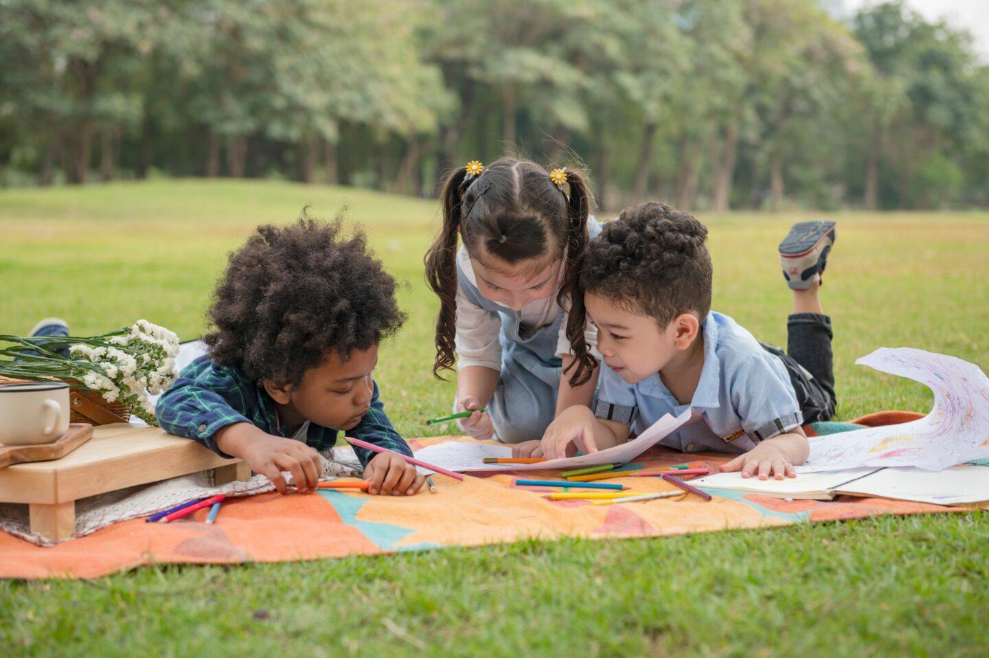 4 ways to help your child be a good friend three kids playing in grass outside making art