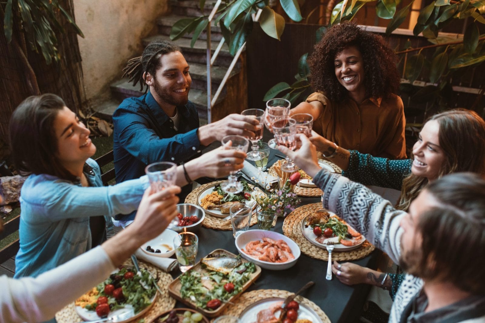 6 tips for stress-free entertaining when you’re feeding a crowd people-clinking-glasses-around-a-dinner-table