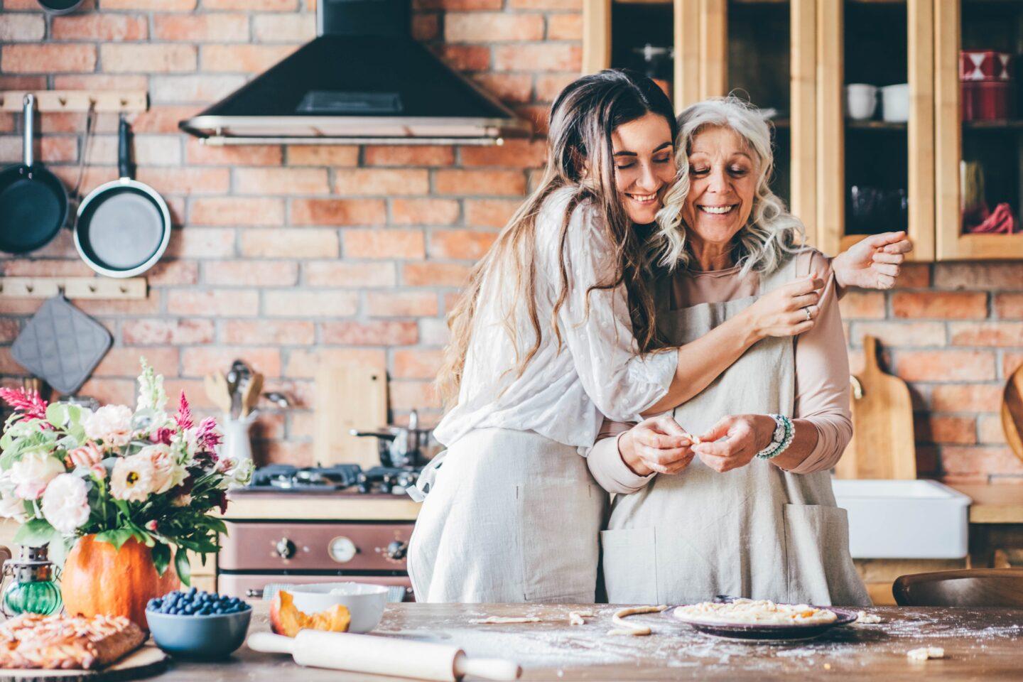 How to navigate the 2021 holiday season—safely daughter hugging mother in the kitchen