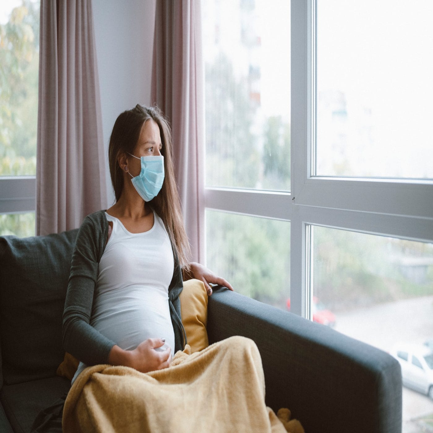 The FDA warns pregnant women or those who may become pregnant should not take the Merck Covid pill Worried pregnant woman with protective face mask at home.