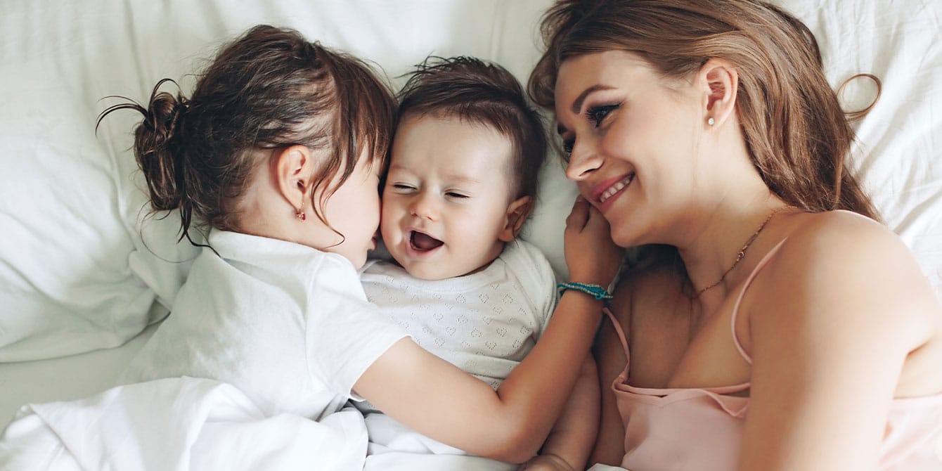 I’m done with New Year’s resolution pressure smiling mom in bed with two kids- new year's resolution list
