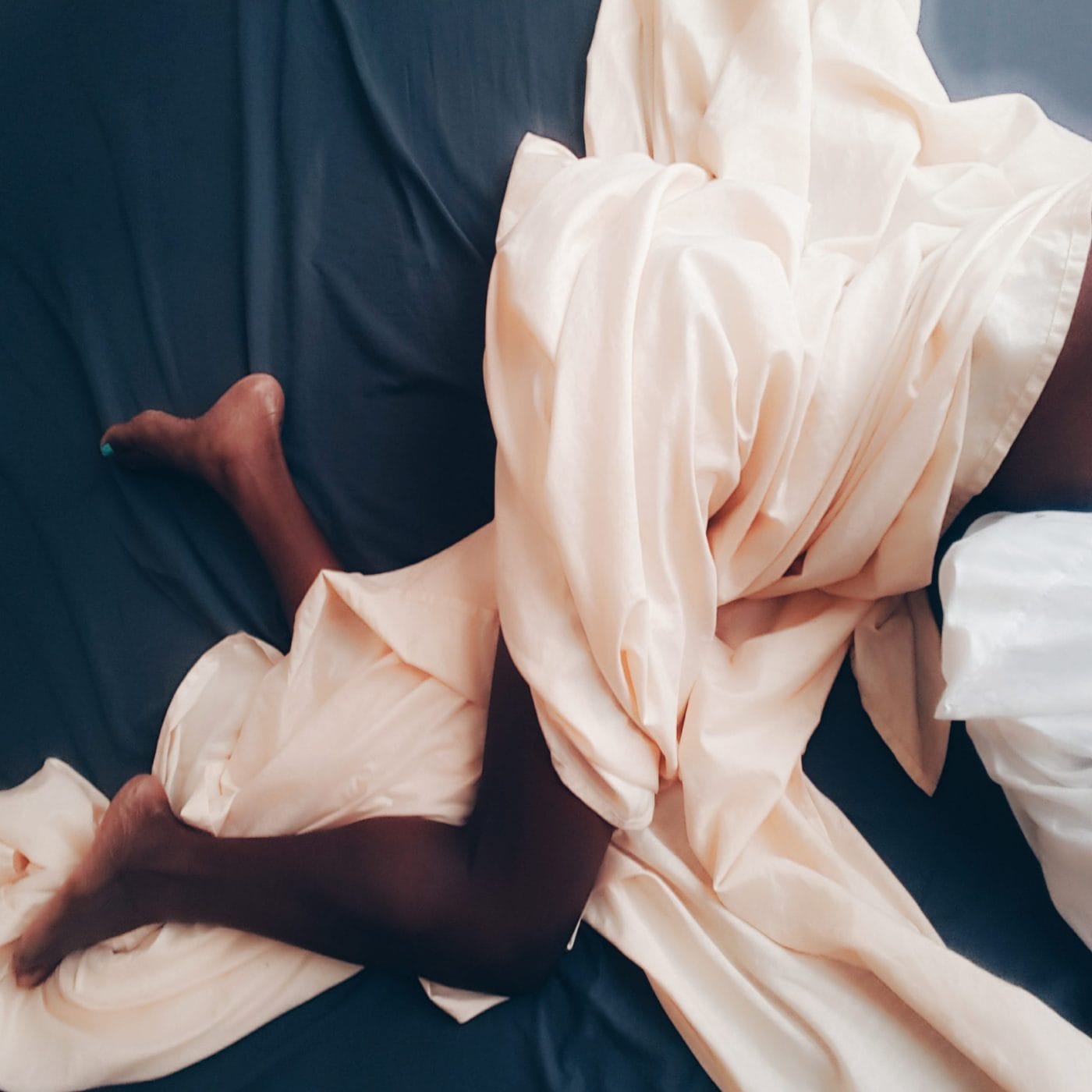 Is it safe to masturbate during pregnancy? woman laying in bed tangled in bedsheets masturbation during pregnancy