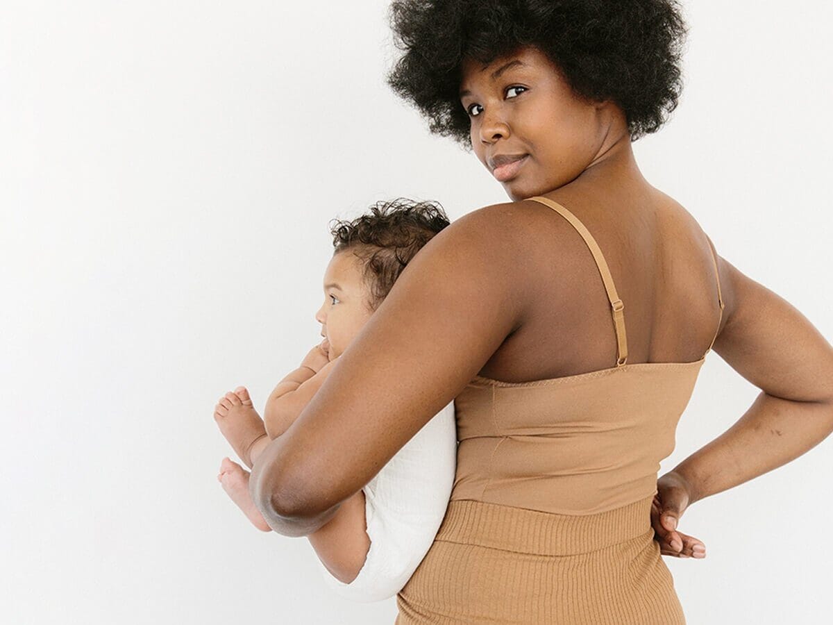 14 nursing tank tops you’ll wear every single day mom holding a newborn looking over her shoulder - best nursing tanks