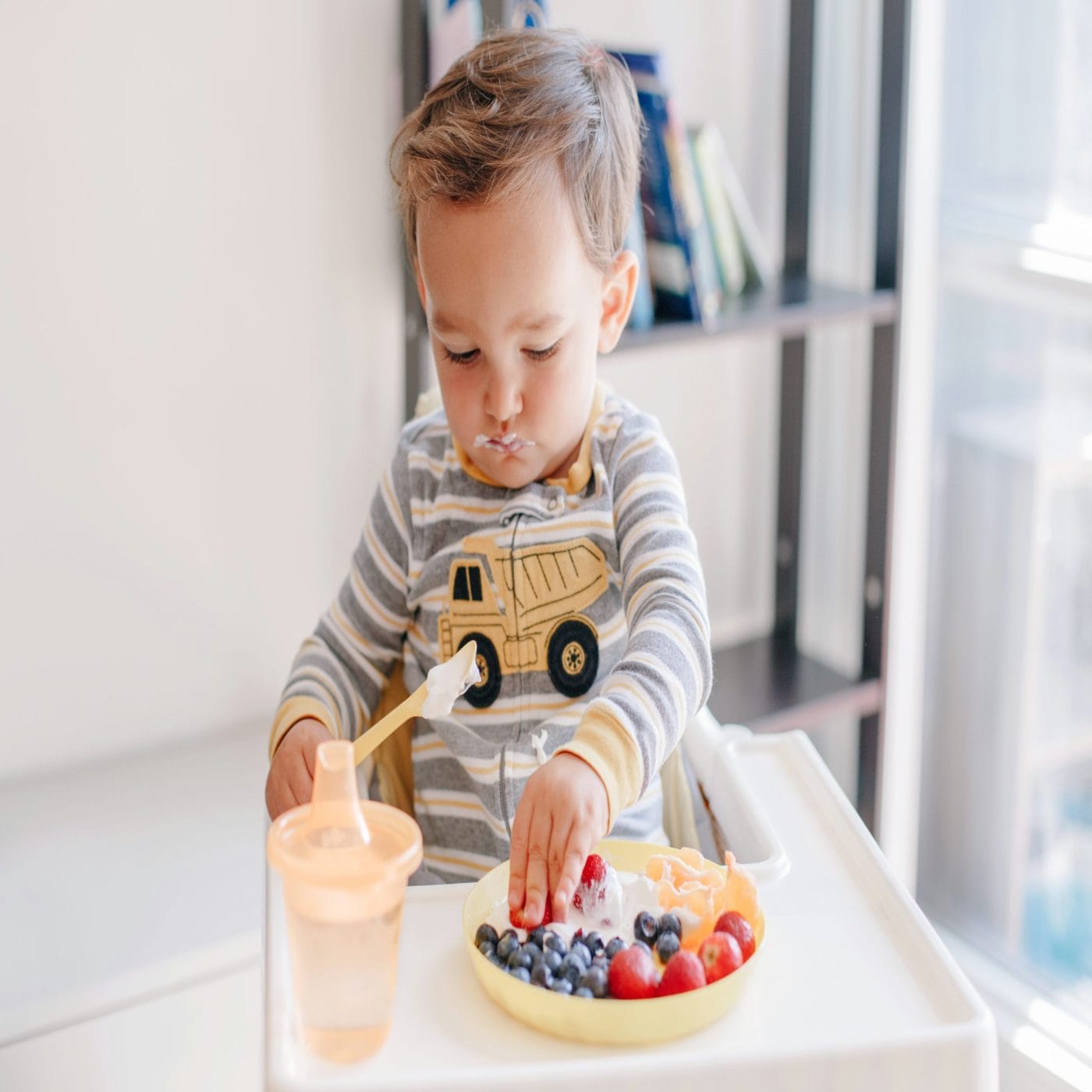 Actually, please *do* let your kids play with their food playing with food - baby eats yogurt and blueberries in high chair