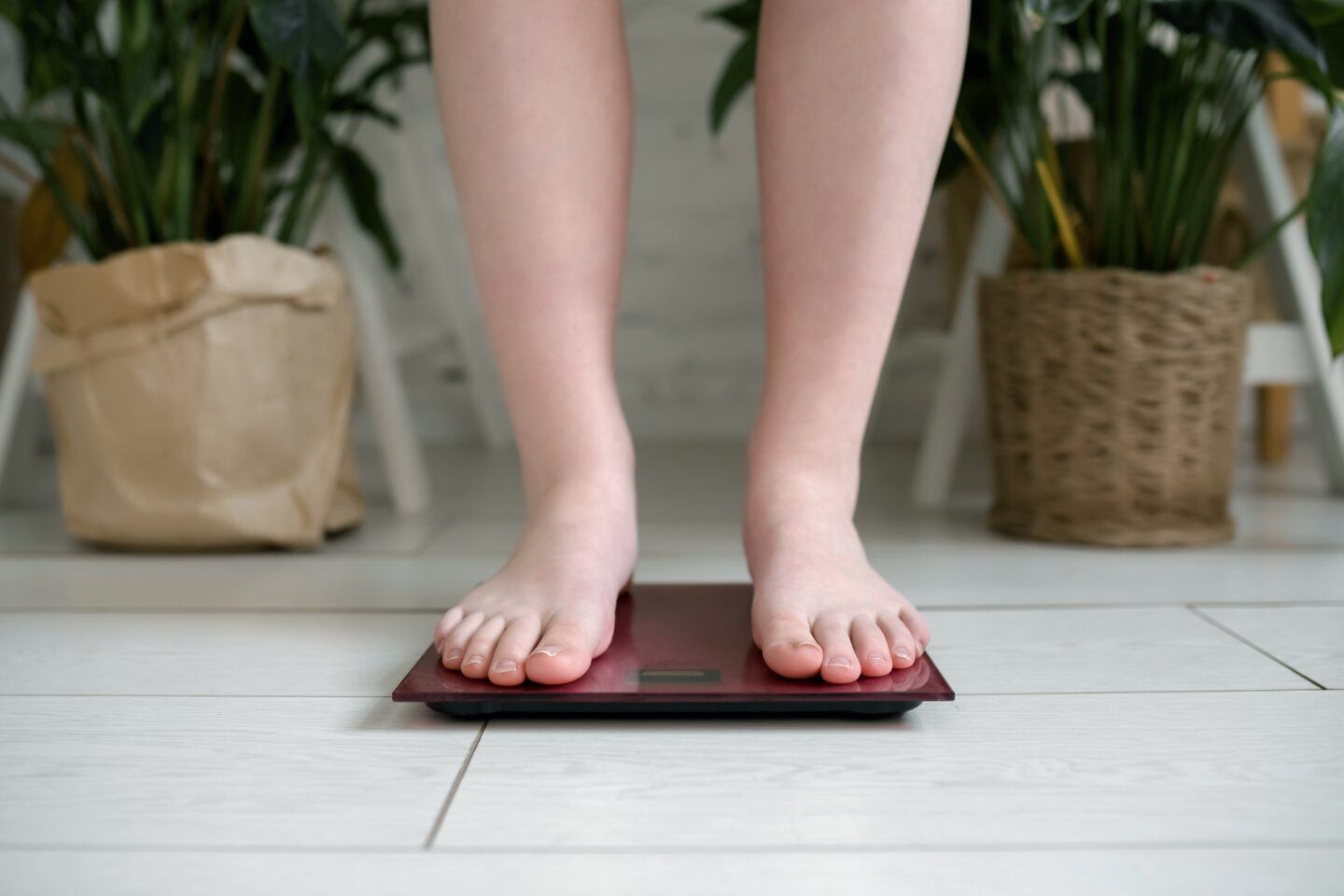 Pressured to lose weight before fertility treatments? One study shows it’s not necessary weight loss: woman stands on scale at home