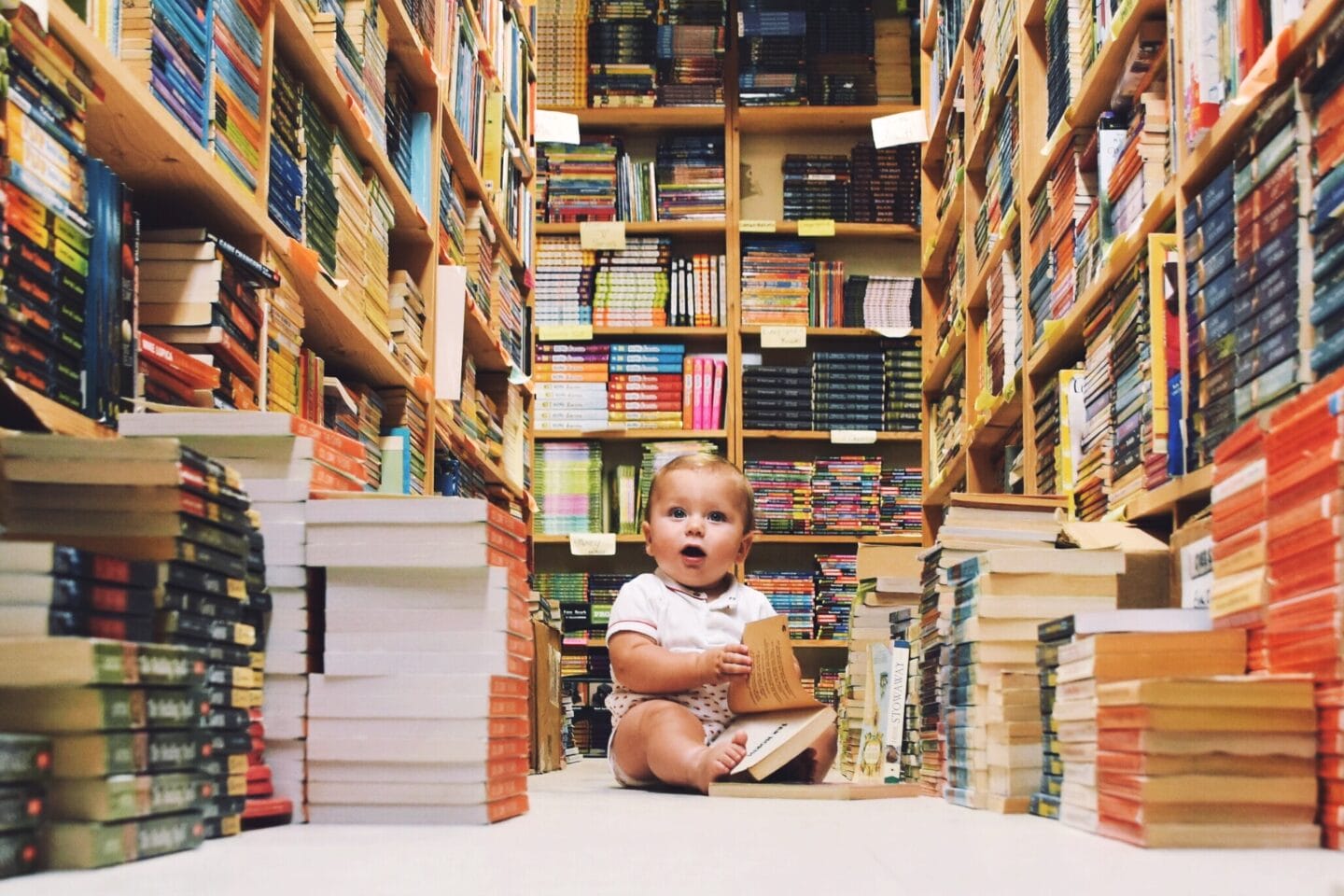 45+ baby names that mean wisdom, intelligent and brilliance baby sitting amongst books in a library