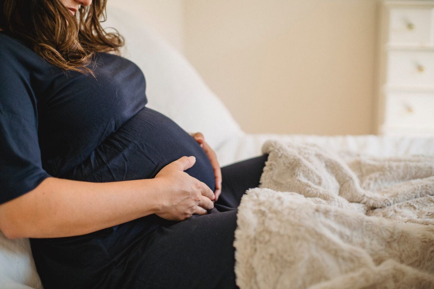 Dreading pregnancy or childbirth? It may be tokophobia  tokophobia: pregnant woman holding baby bump at home in bed