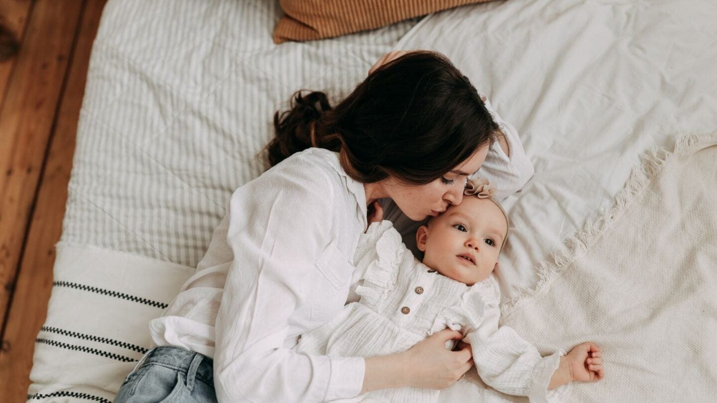 10 things new mamas don’t want to hear new mama: mother laying on bed kissing baby