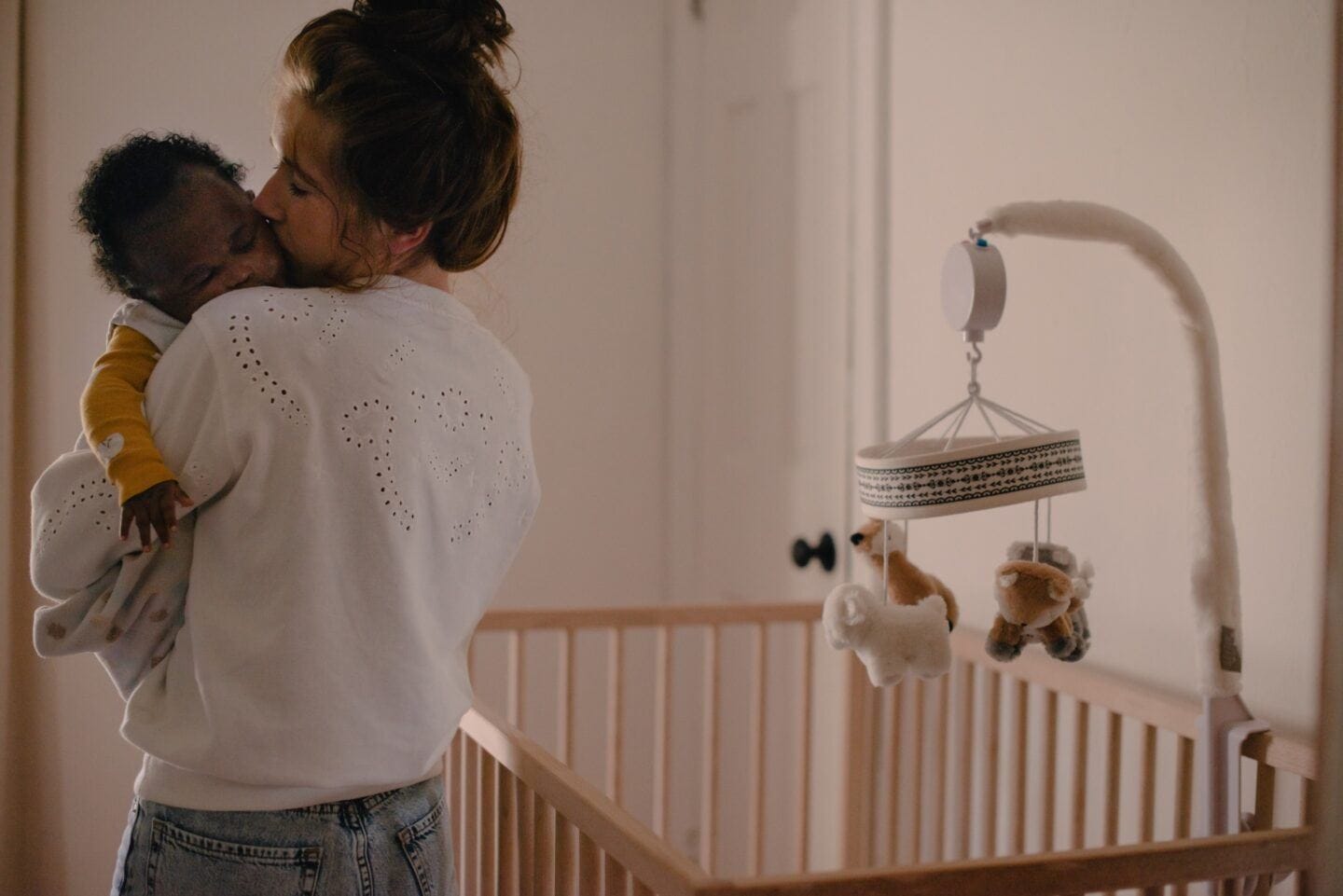 It’s OK to prioritize your baby’s nap schedule sleep schedule: mom holding sleeping baby next to crib