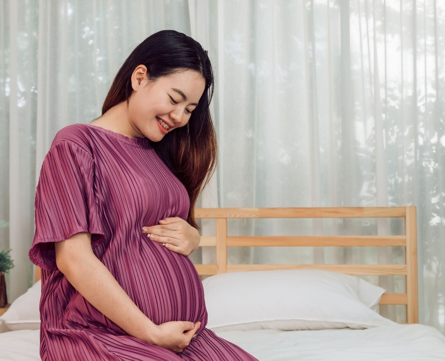 It’s science: Probiotics in early pregnancy may reduce morning sickness pregnant woman holding belly sitting on bed at home