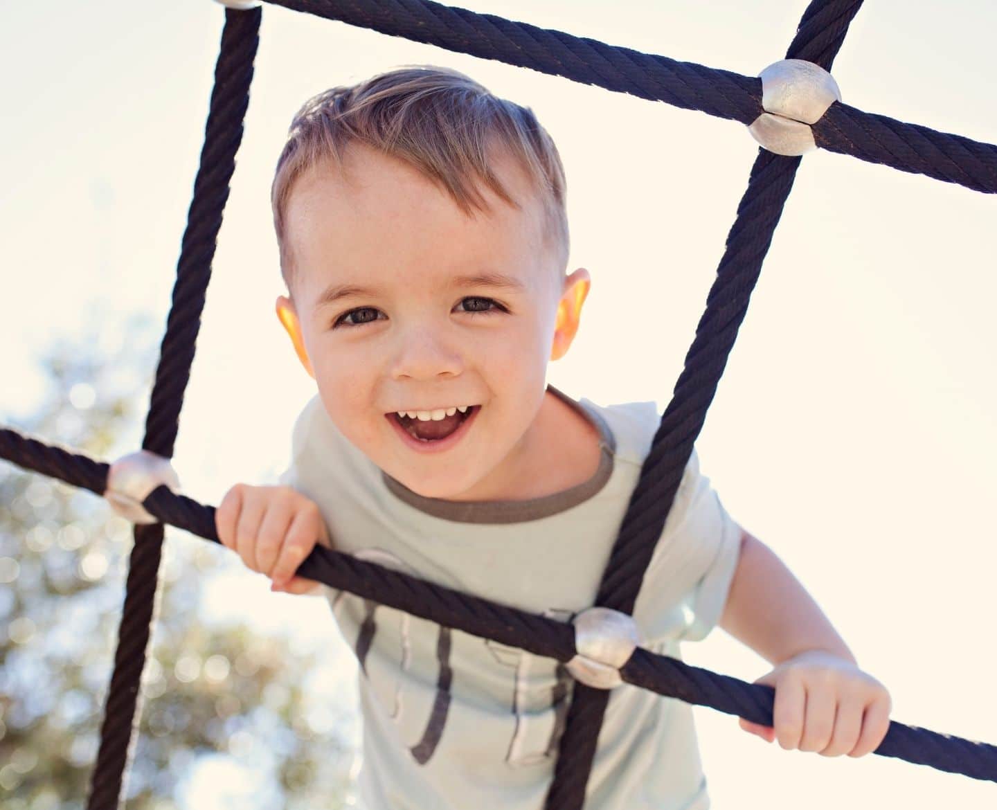 Want a safe summer camp experience? What to look for—and what to avoid boy climbing on rope structure outside in summer