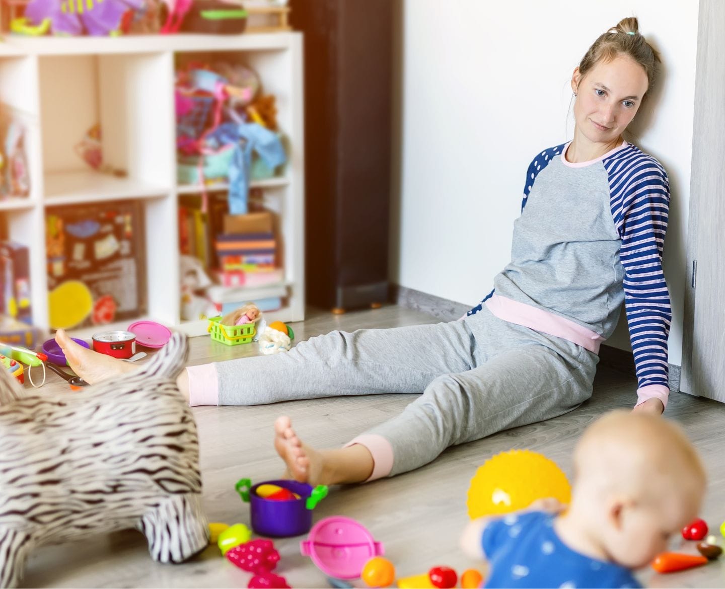Getting rid of my kids’ clutter makes me a better mom clutter: mom sitting on floor with baby surrounded by toys
