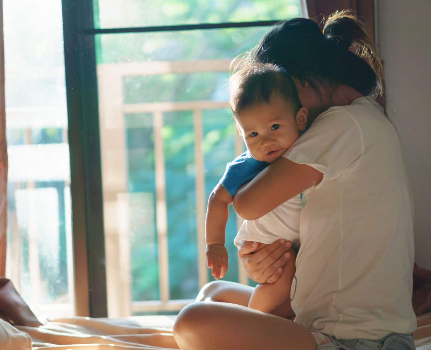 Motherhood feels lonelier than ever lonely: mom holding baby while sitting on bed