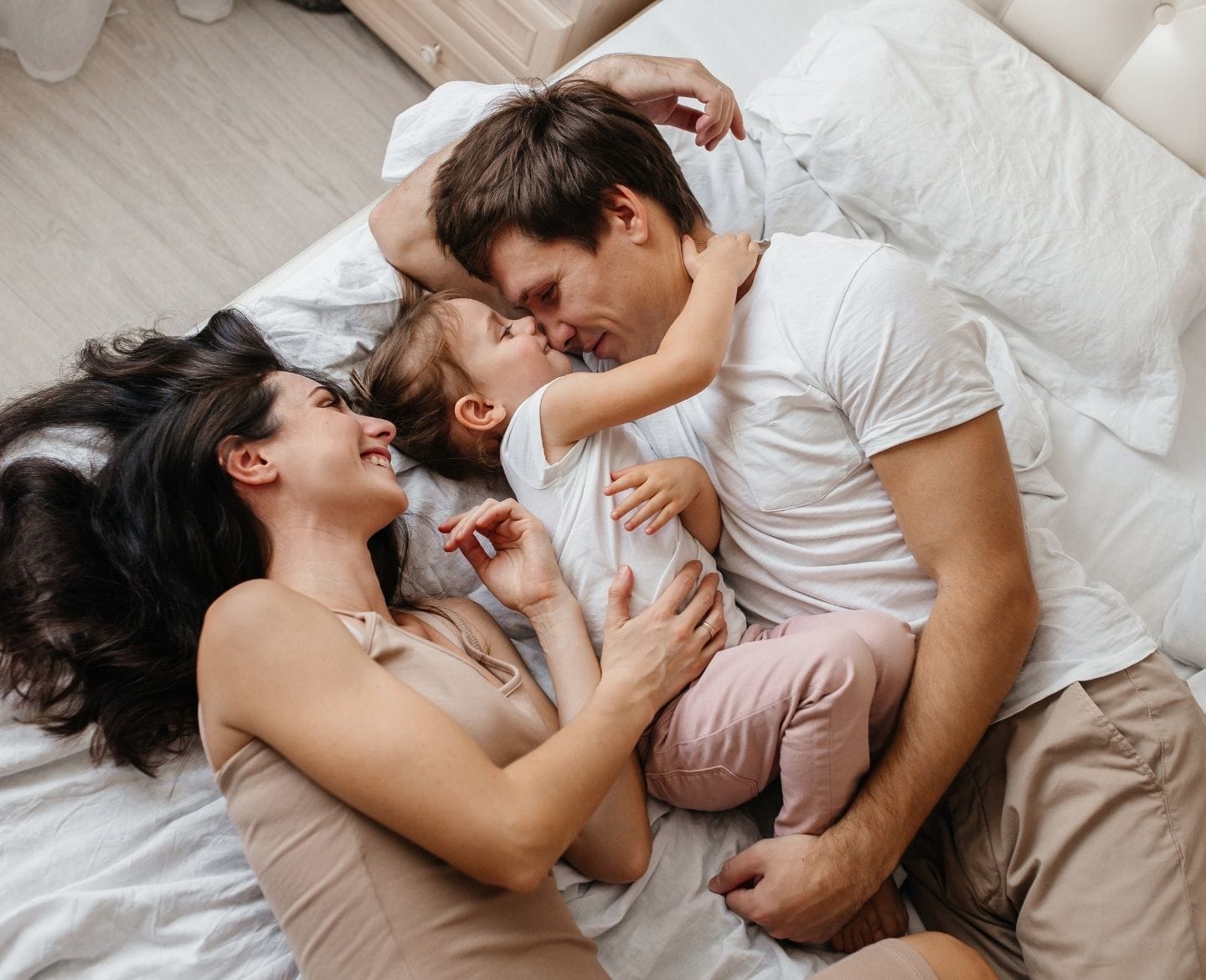 5 things we want our child to always know about our home mother, father and daughter laying on bed smiling