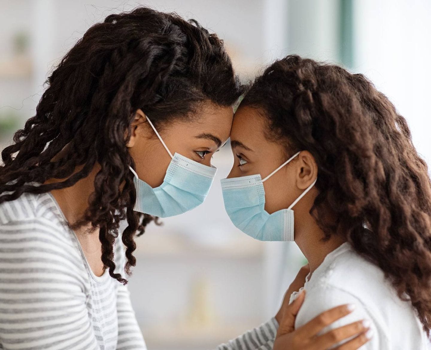 Mothers are burnt out—but is it possible to change that narrative? mom and daughter looking eye to eye while wearing masks