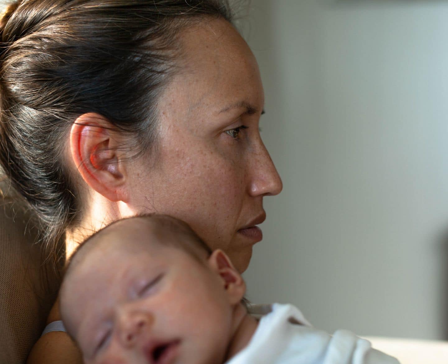 ‘Critical’ TRIUMPH for New Moms Act moves one step closer to becoming law maternal mental health: mother holding sleeping baby at home