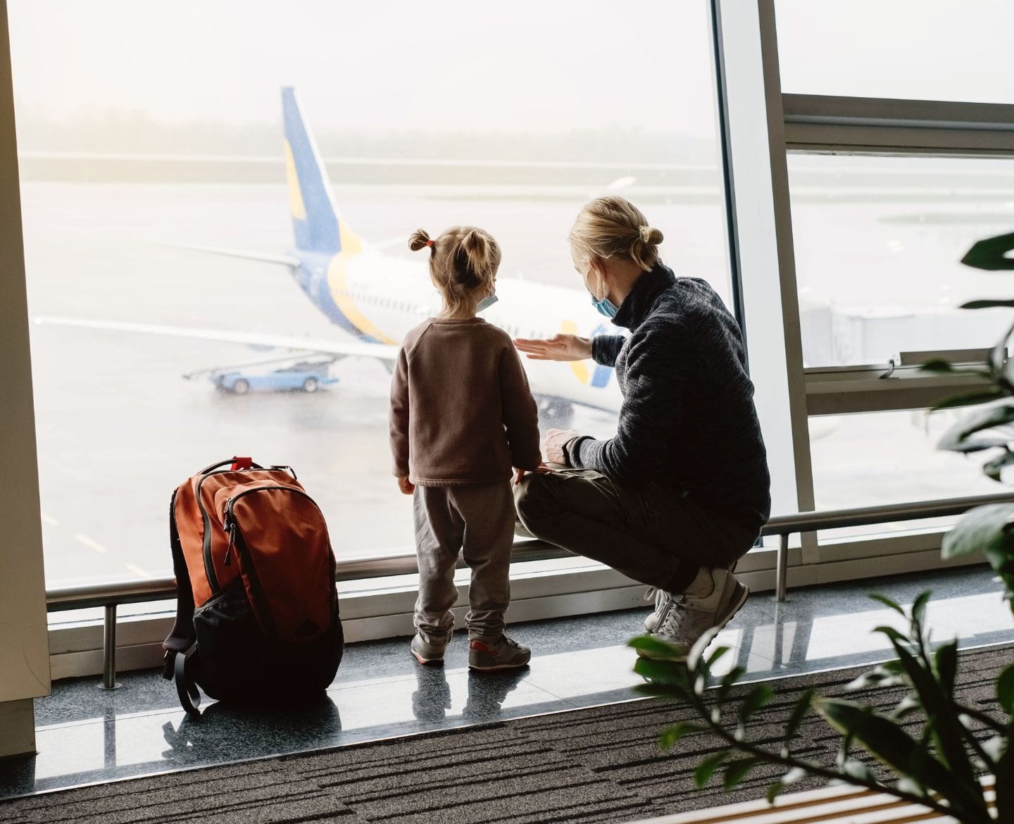 A sleep scientist shares her best sleep tips for traveling with babies and kids Mother with child in airport looking at airplane