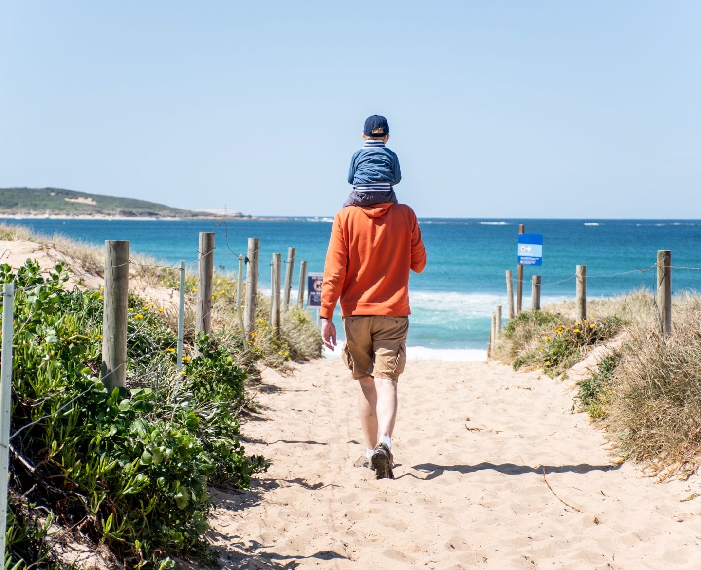 My husband gets praised for traveling alone with our kids—I don’t father walking on beach with son on his shoulders