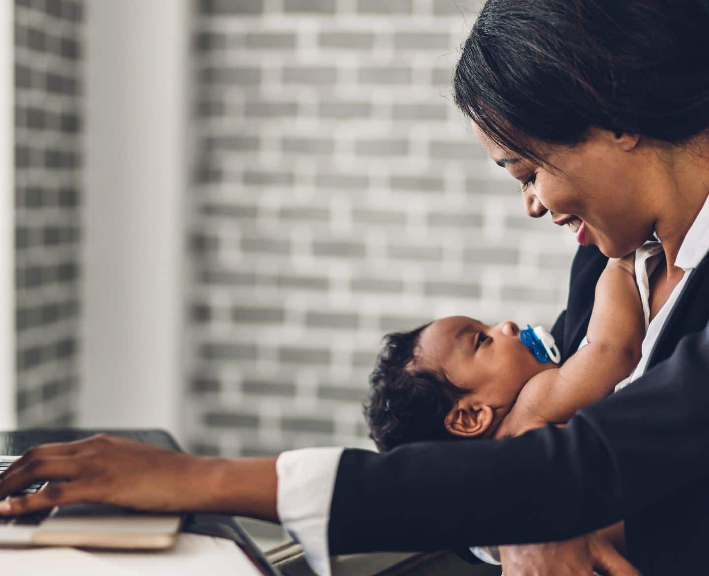 Forcing employees back to the office is insulting and harmful to working parents working mom at computer with baby