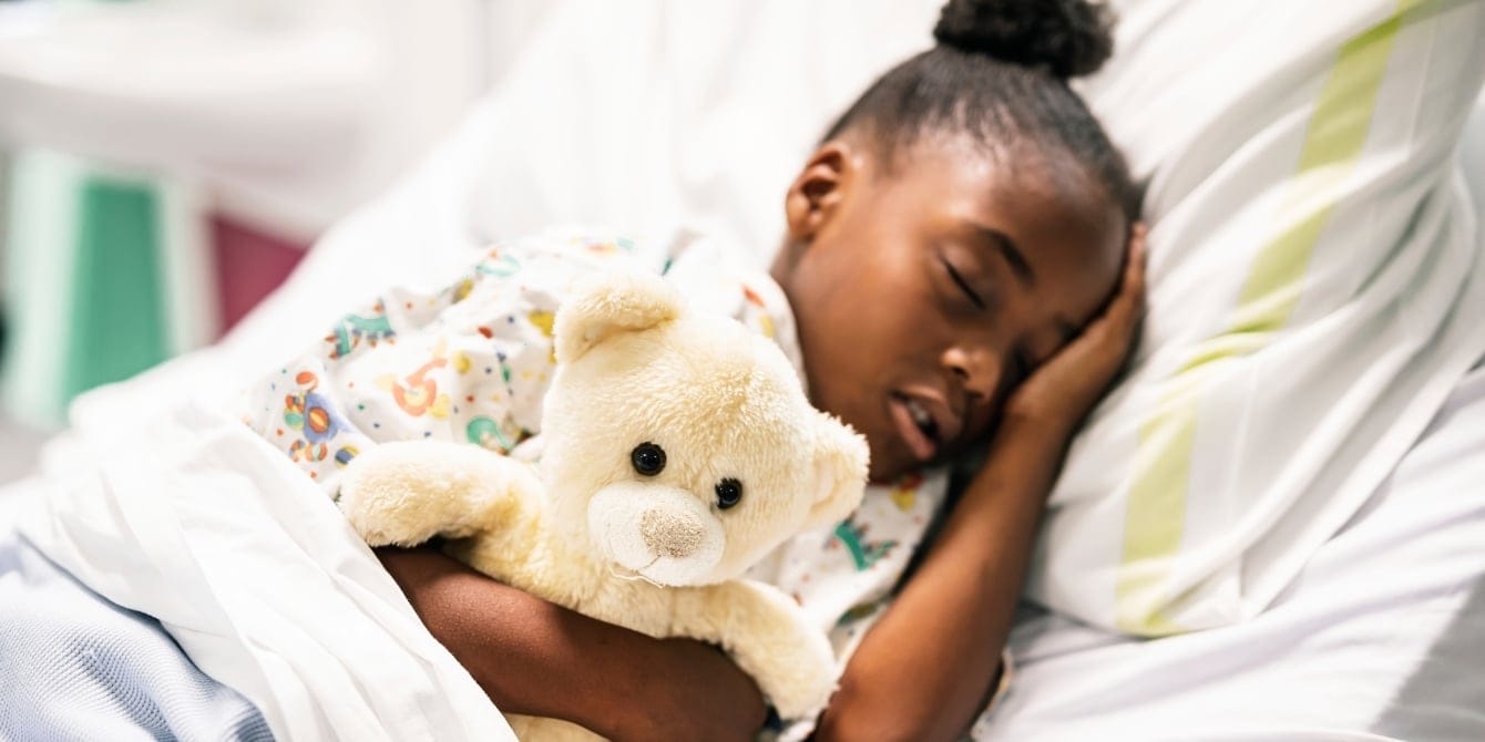 The one thing your child needs to get ready for kindergarten? More sleep, says AAP young girl sleeping in bed with teddy bear - sleep for kindergarten success
