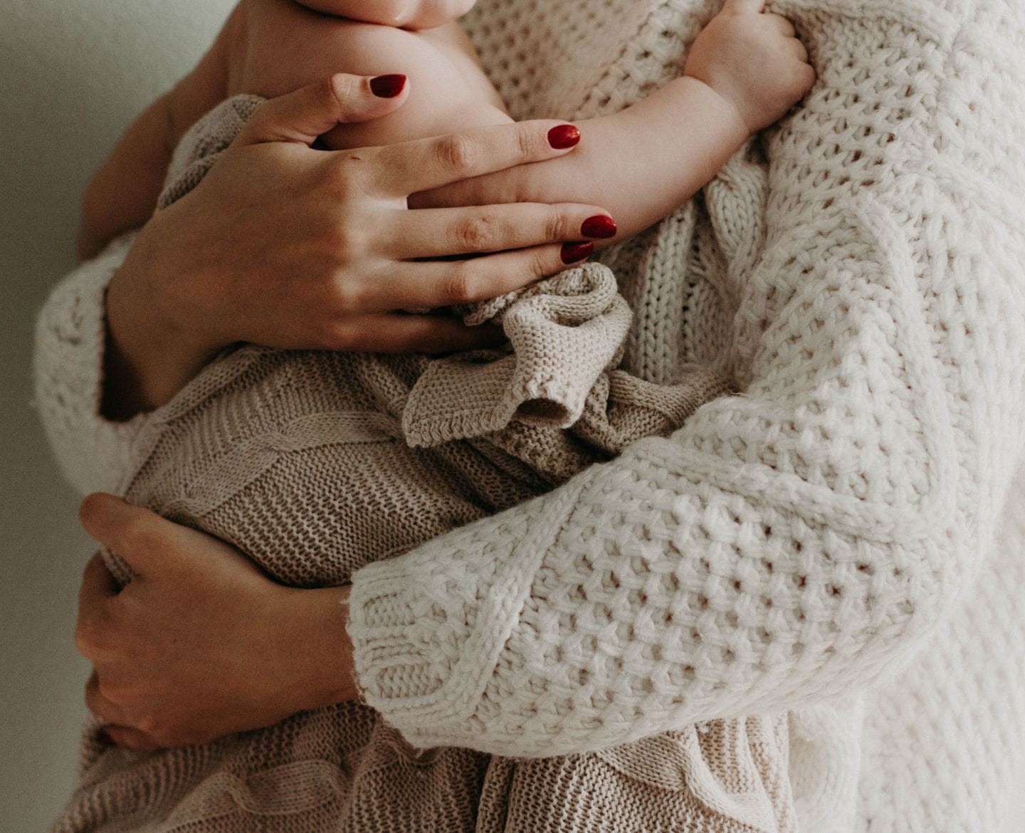 ‘Failure to thrive’ is a harmful and unhelpful term for my child woman holding baby against her chest wrapped in a blanket