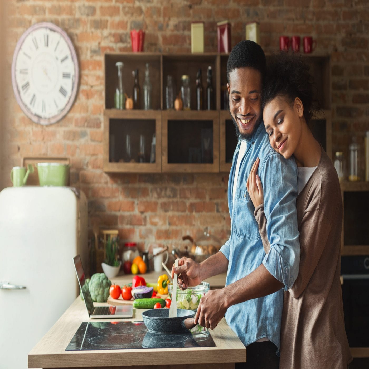 5 ways to optimize your health before pregnancy, according to an OBGYN woman hugging partner while cooking dinner