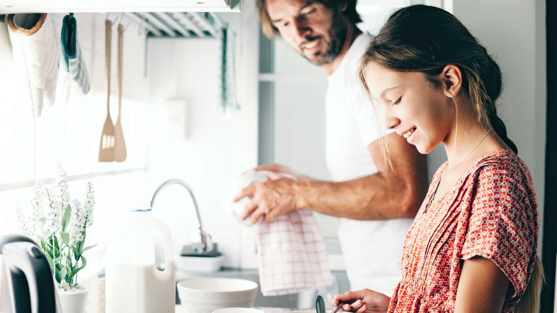 Dad and daughter in kitchen bivalent boosters for kids - Motherly