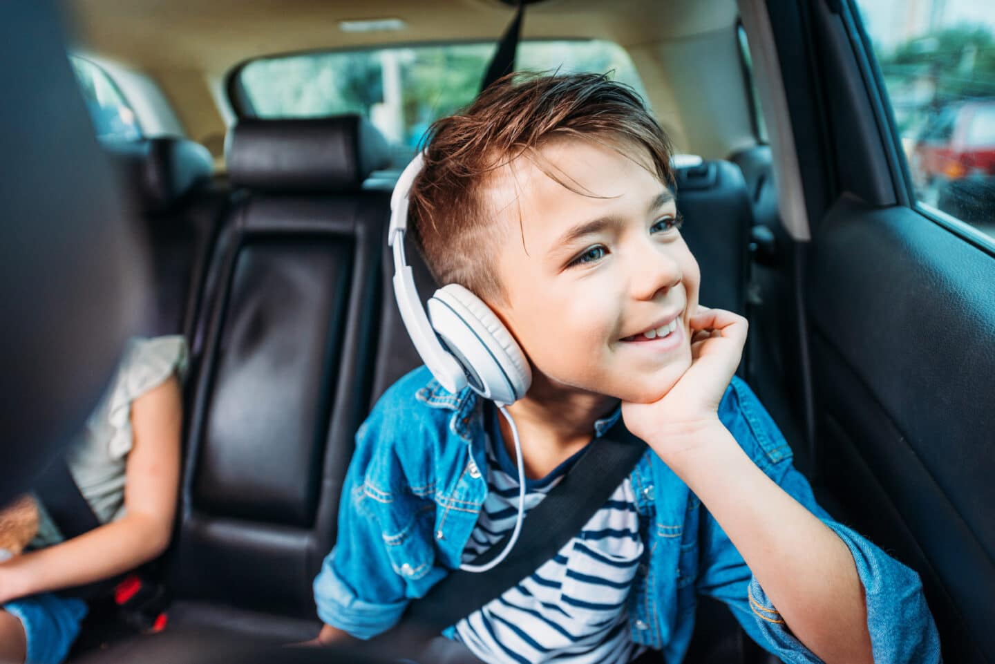 Turn it up: The best music-focused podcasts and audiobooks for kids kid in car with headphones-audiobooks for kids