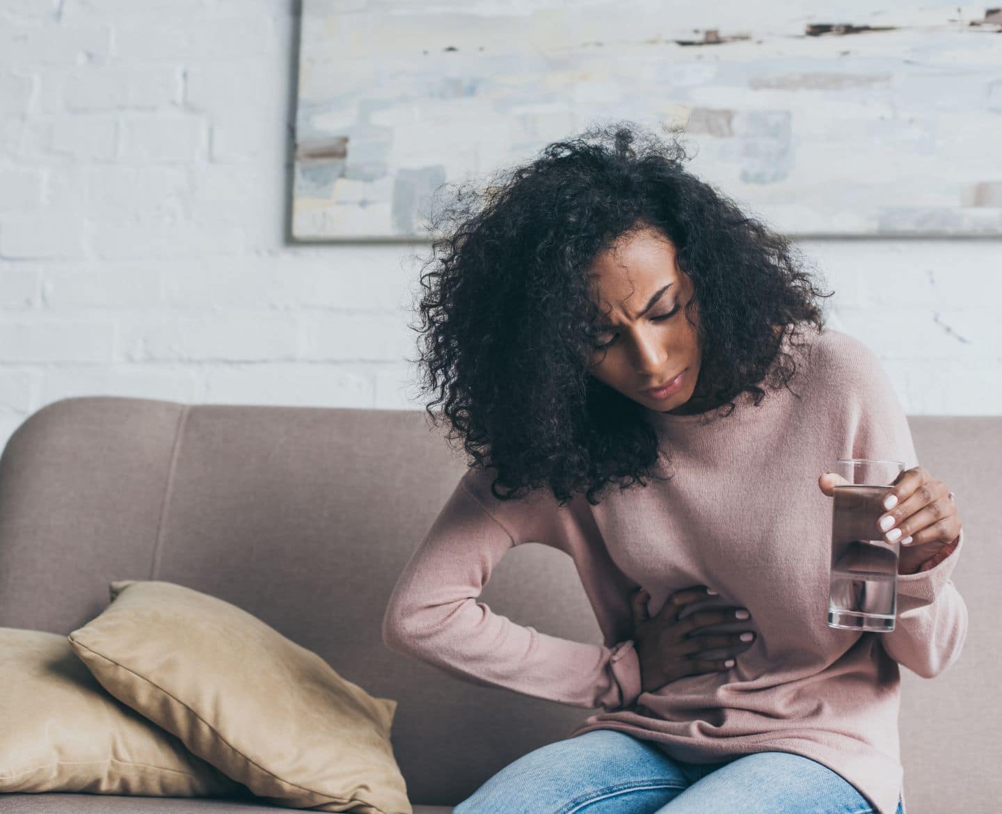 10 common fibroids myths, dispelled by an ObGyn woman holding her abdomen - fibroids