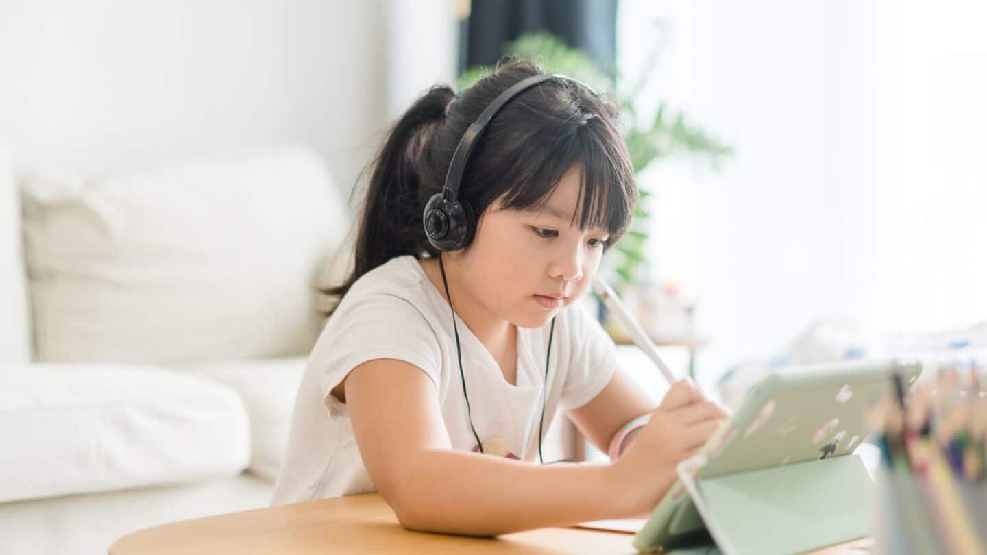 8 money apps for kids to help teach them about money management girl working on tablet - money apps for kids