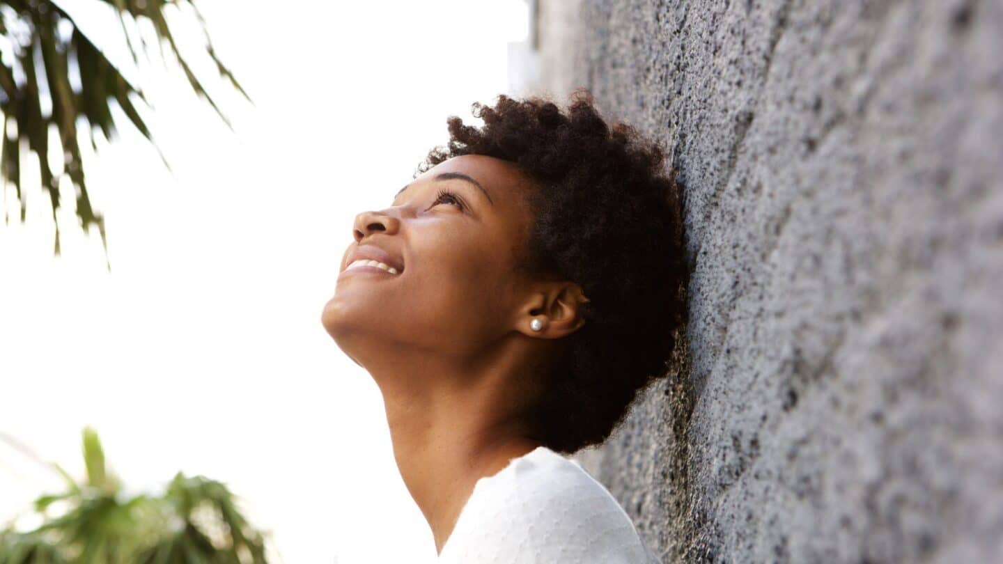 4 phrases confident women tell themselves when they don’t get the job they dreamed of woman against a brick wall looking up at the sky