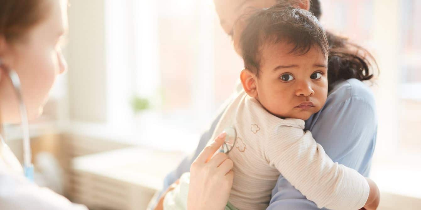 FDA approves RSV shot for infants doctor listening to baby's lungs with stethoscope when talking with mother about rsv shot