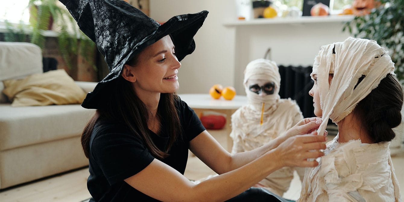 10 Halloween safety tips and Amazon buys for a spooktacular night mom helping her kid put on mummy Halloween costume keeping Halloween safety in mind