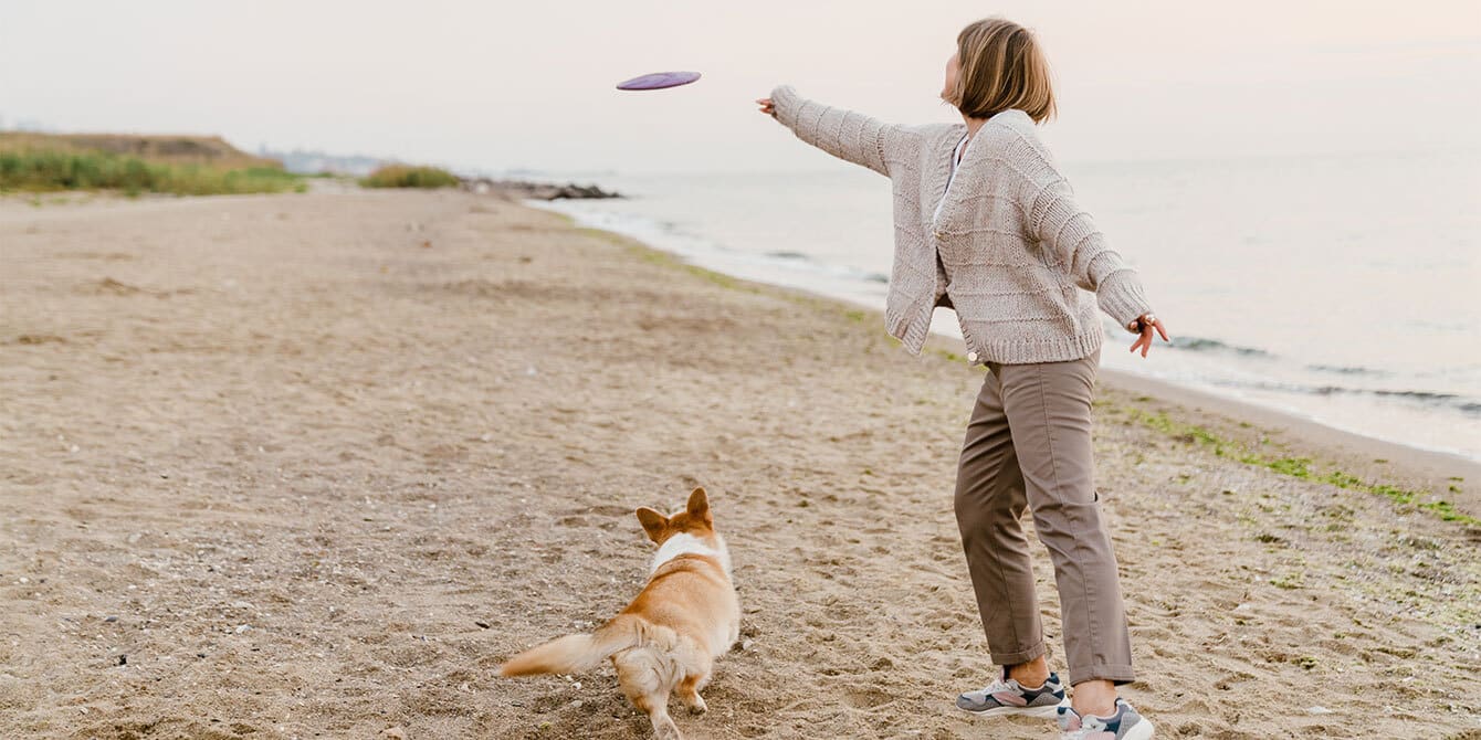 15 reasons why it isn’t ‘selfish’ for me to not want a child right now child free woman on beach playing frisbee with dog