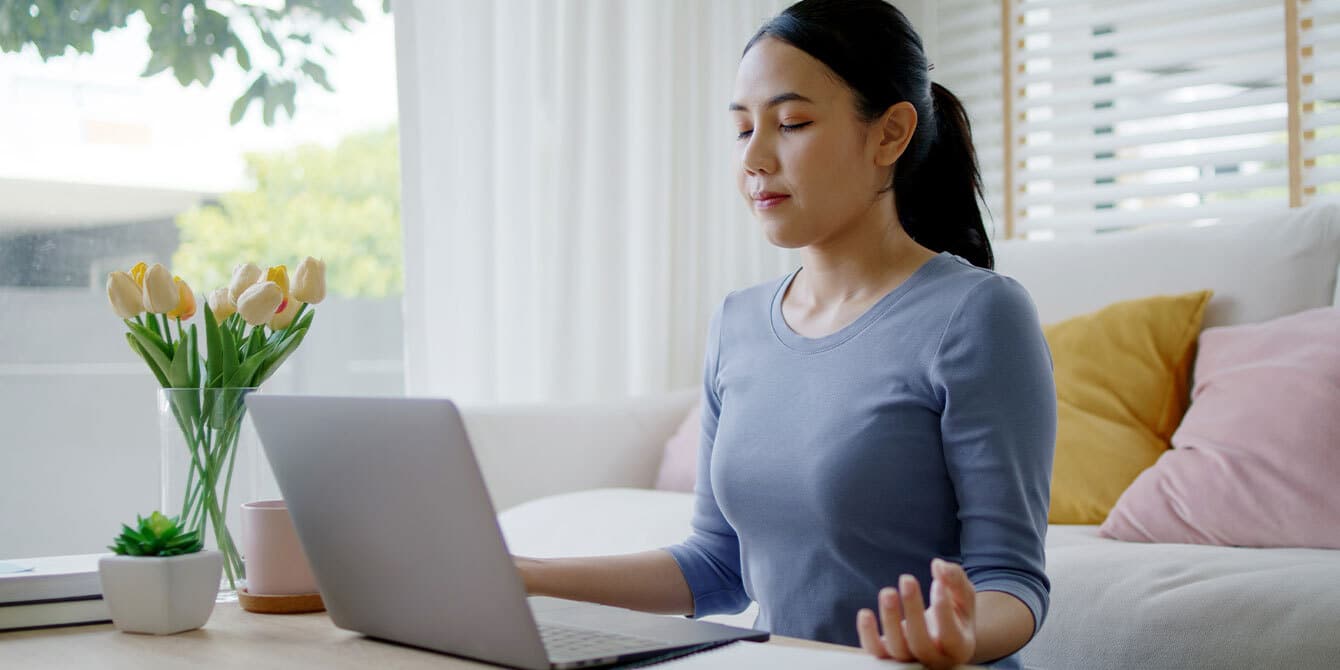 How to cope with anxiety in a high-stress work environment woman coping with anxiety and work stress by meditating in front of a computer