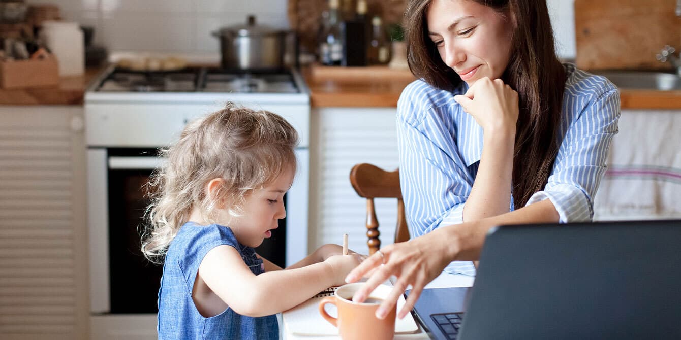 5 reasons why hybrid schedules are my dream as a working mom Mom working hybrid schedule from home with child coloring.