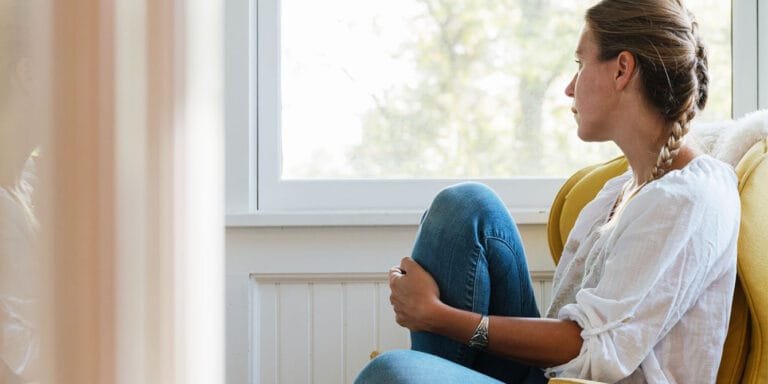 The unexpected grief triggers I encountered after my pregnancy loss grief-stricken woman sitting and staring out of a window
