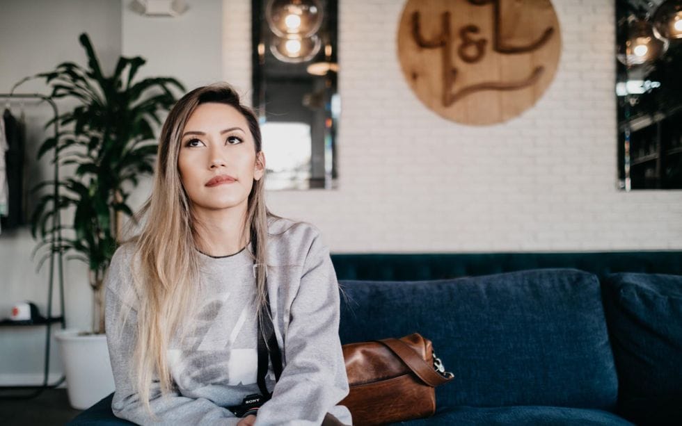 woman sitting on couch thinking - Motherly