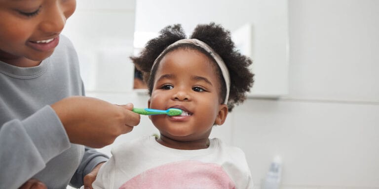 How ‘habit stacking’ can improve your family’s routines—and happiness mom helping toddler brush her teeth - habit stacking