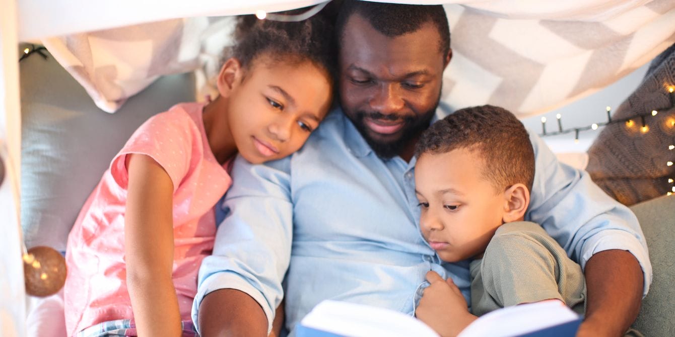 This 4-day work week trial shows men did A LOT more childcare dad laying in bed with two kids reading-4-day work week trial