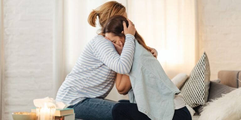 The youth mental health crisis is improving—slightly, CDC says mom hugging teen daughter to support teen mental health