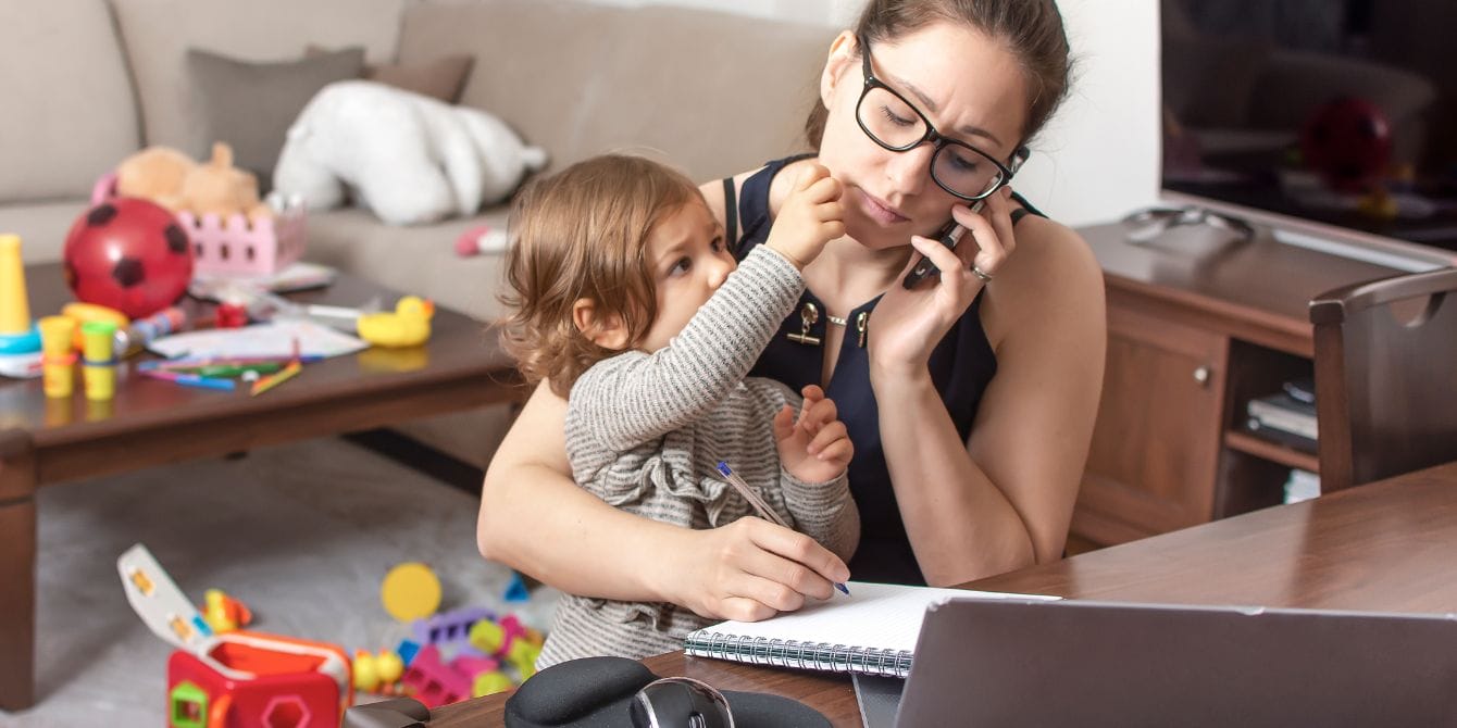 1 in 4 parents say they’ve been fired for childcare challenges mom struggling to work with baby on lap- annual cost of childcare