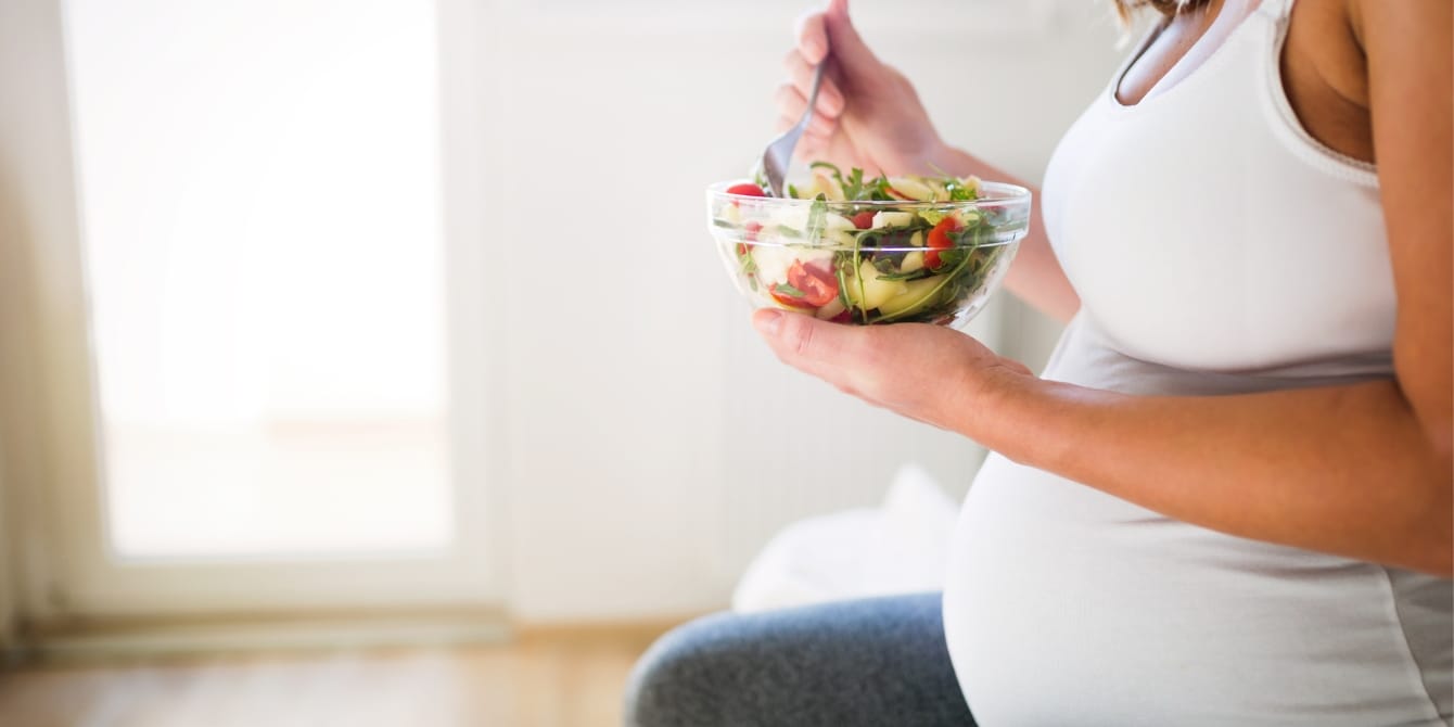 Eating a Mediterranean diet could increase your chances of becoming pregnant, studies show pregnant woman eating a green salad - mediterranean diet for fertility