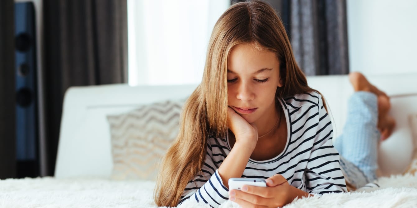 My daughter is 10—the average age children receive a smartphone teen looking at smartphone - wait until 8th