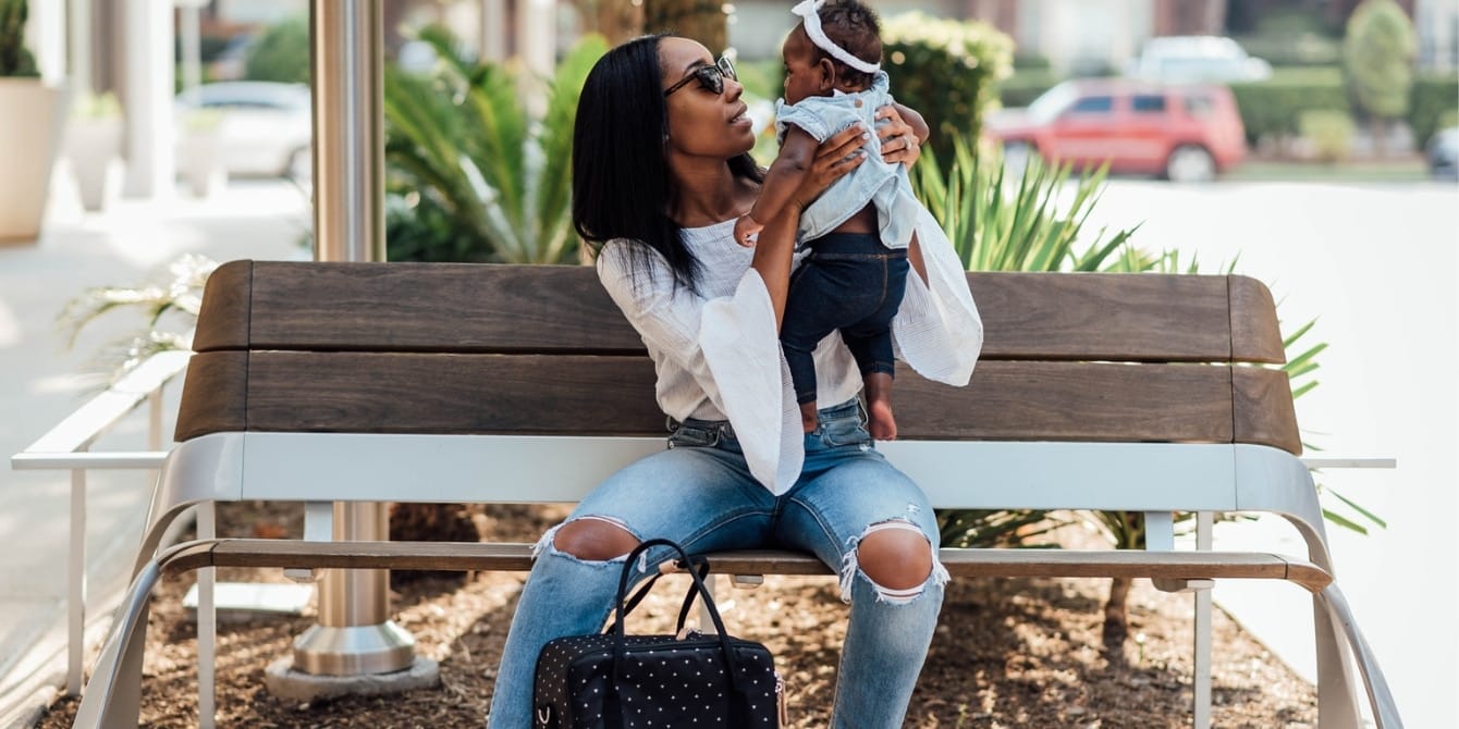 It’s not the responsibility of moms to fix the economy Mom holding baby on bench