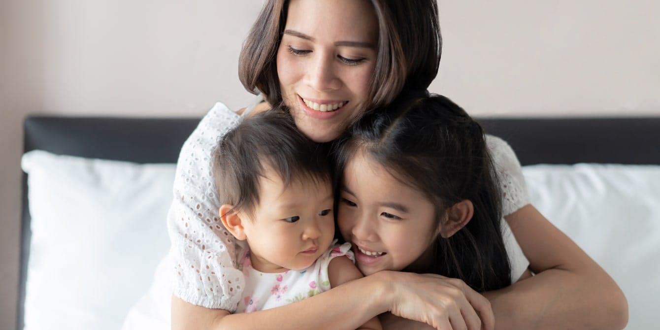 3 ways ‘peaceful parenting’ helps us heal alongside our kids mom hugging her two kids - peaceful parenting helps parents and kids