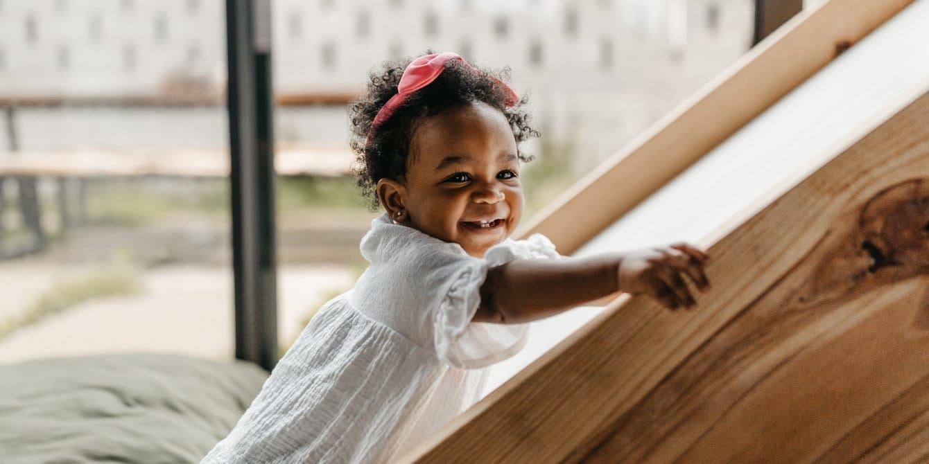 18-month-old milestones smiling toddler climbing up an indoor slide - 18-month milestones