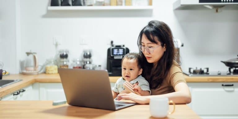 Parental leave isn’t enough mom working with baby on her lap another reason why parental leave isn't enough for working parents